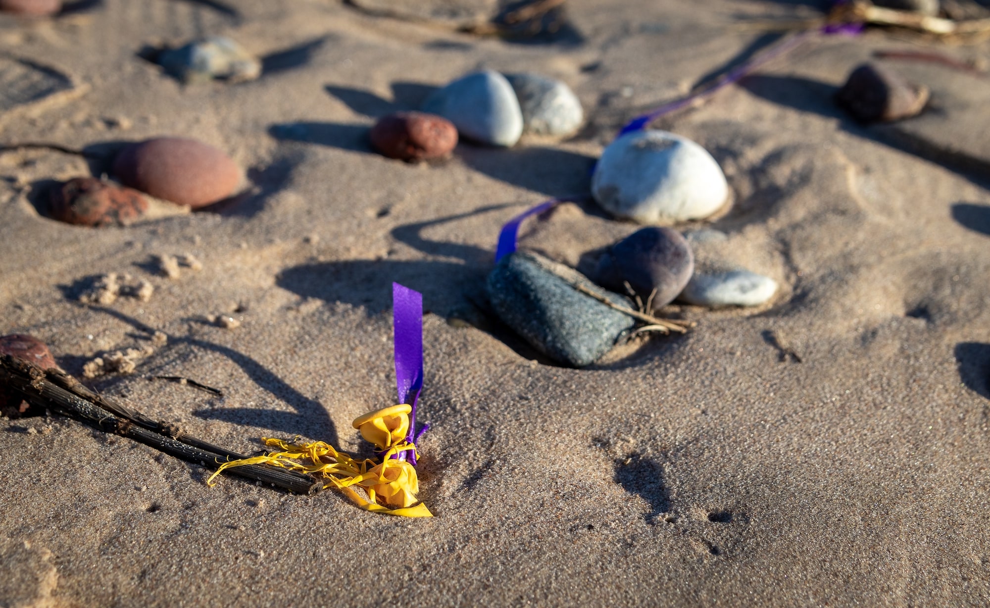 Image of a Yellow Deflated Balloon Stranded Near The Shoreline of a Beach